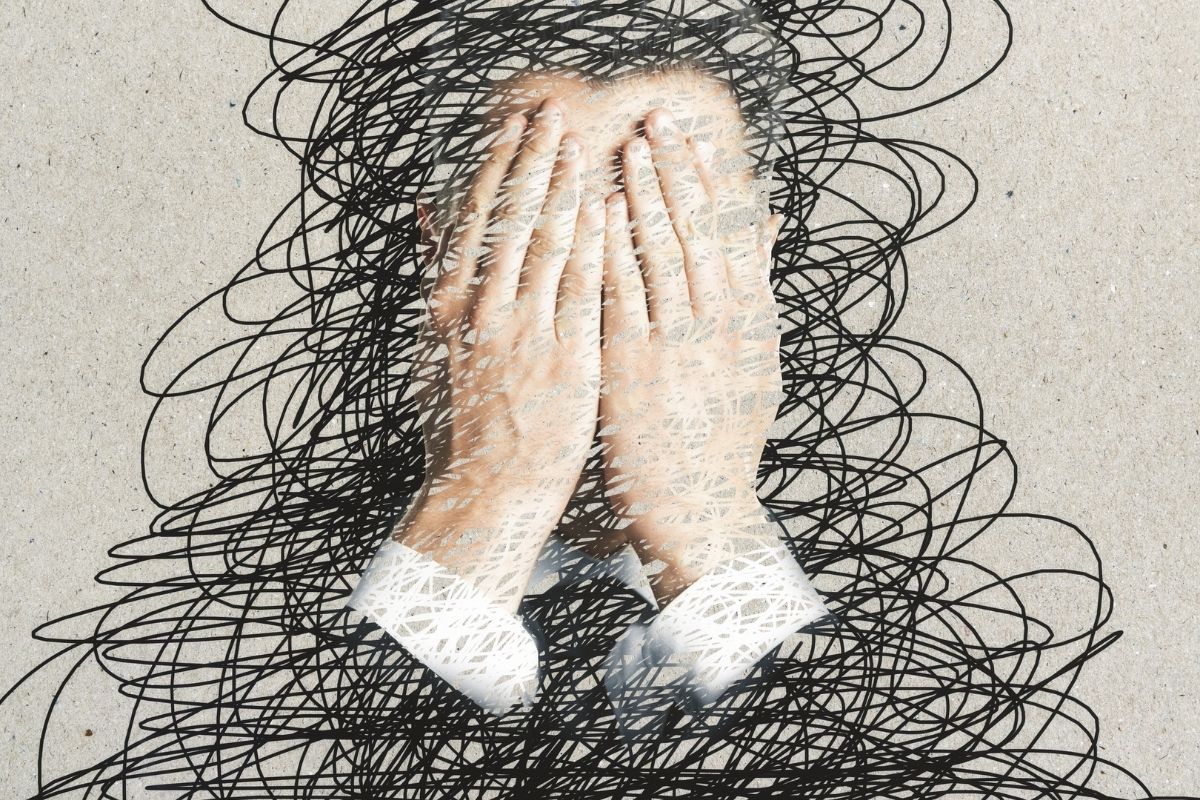 A person covering their face with scribbles all around them.
