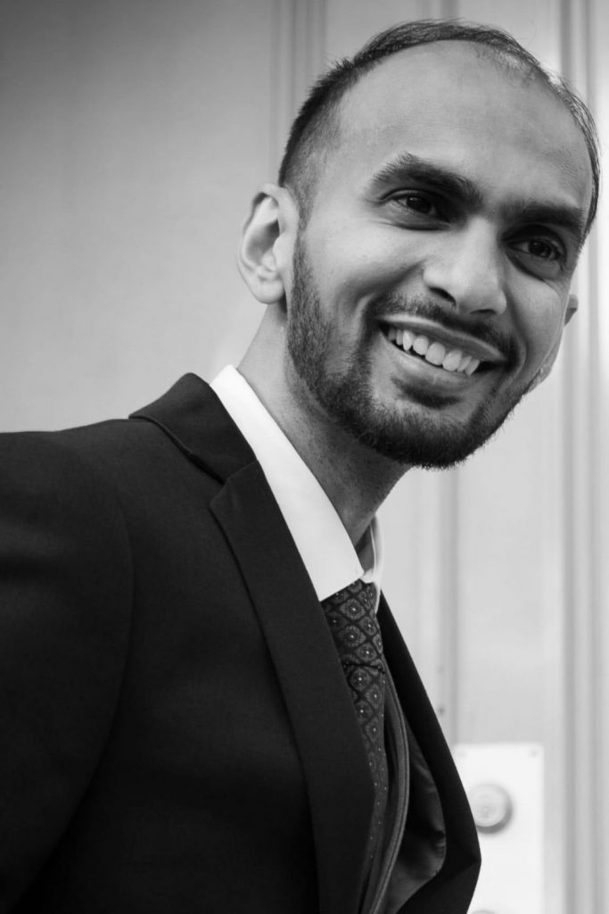 A groom in black and white smiling away from the camera.