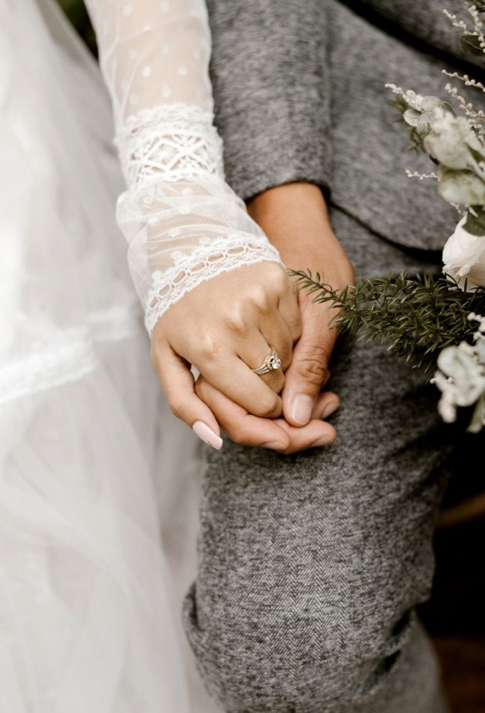 Close up of hands where the groom is holding his bride's hand.