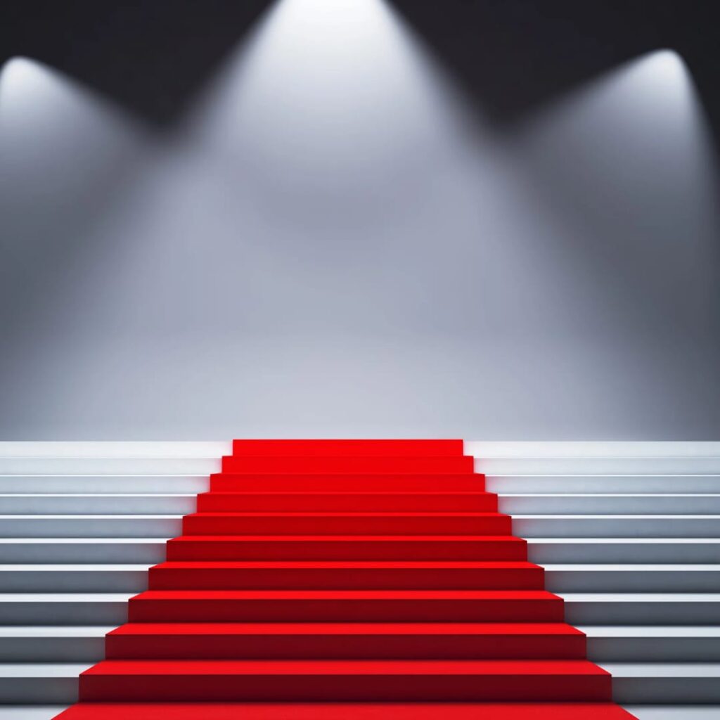 Wide stairs with red carpet leading up to a stage and spot lights.